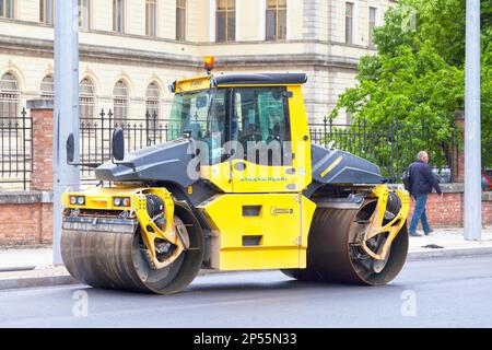 Varna, Bulgaria - Maggio 16 2019: Un compattatore Bomag spianando l'asfalto appena steso su una strada del centro. Foto Stock