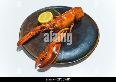 piatto nero con aragosta e limone su di esso, concetto di pesce. Foto di alta qualità Foto Stock