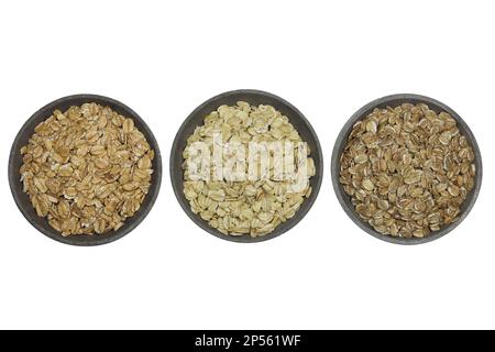 fiocchi di cereali (farro, avena, segale) in ciotole di cemento isolate su fondo bianco Foto Stock