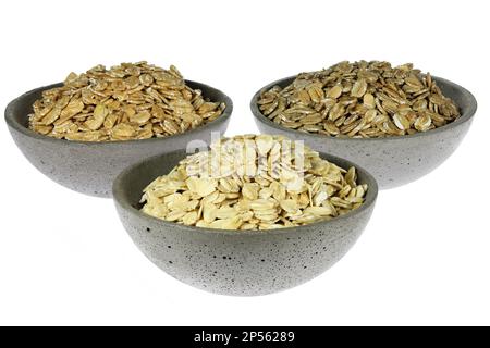 fiocchi di cereali (farro, avena, segale) in ciotole di cemento isolate su fondo bianco Foto Stock