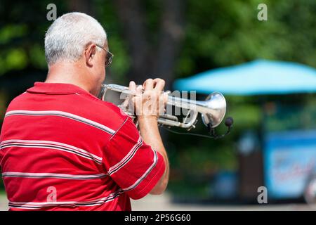 Kiev, Ucraina - 06 2018 luglio: Musicista che suona con la sua tromba in un parco pubblico. Foto Stock