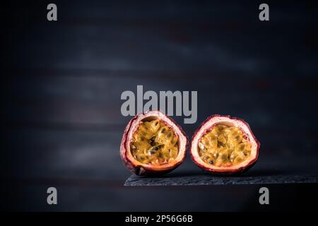 Primo piano di un frutto della passione fresco a metà isolato su uno sfondo di legno scuro. copia spazio per il testo Foto Stock