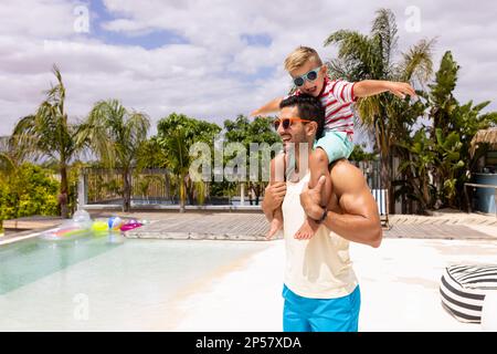 Buon padre e figlio biraciale che giocano in piscina Foto Stock