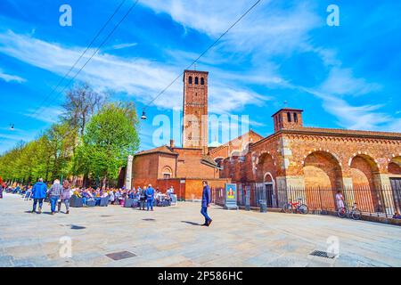 MILANO, ITALIA - 11 APRILE 2022: Ristoranti all'aperto in Piazza Sant'Ambrogio con torri della Basilica di Sant'Ambrogio sullo sfondo, il 11 aprile a Mila Foto Stock