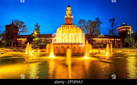 La vista notturna sulla fontana di Piazza Castello con sullo sfondo il Castello Sforzesco illuminato, Milano, Italia Foto Stock