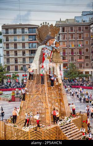 Uomini che collocano offerte di fiori su grande statua in legno replica di Virgen de los Desamparados, Fallas festival, Plaza de la Virgen, Valencia Foto Stock