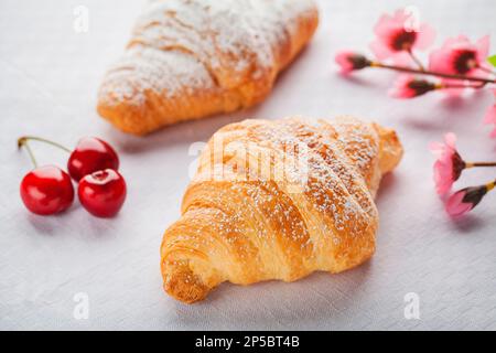 Croissant con zucchero candito, confettura di ciliegie ripieno. Colazione tipica del mattino. Foto Stock