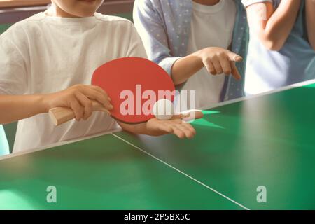 Ragazzino con amici che giocano a ping pong in casa, primo piano Foto Stock