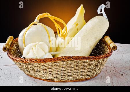 Diversi tipi di formaggi italiani: Scamorza, provolone e caciocavallo con latte vaccino in cesto di legno Foto Stock