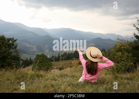 Giovane donna che gode di un bellissimo paesaggio montano, vista posteriore. Spazio per il testo Foto Stock