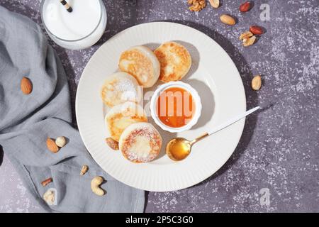 Piatto con gustosi pancake al formaggio casolare, marmellata, latte e noci su fondo grunge Foto Stock