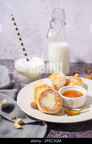 Piatto con gustosi pancake al formaggio casolare, marmellata e latte su fondo grunge, primo piano Foto Stock