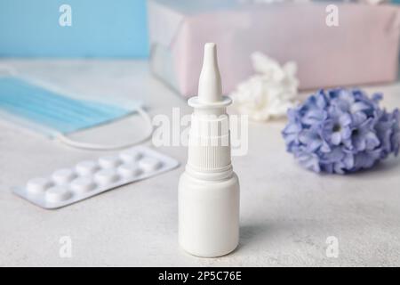 Gocce nasali con pillole su tavolo bianco. Concetto di allergia stagionale Foto Stock