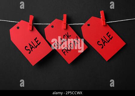 Etichette rosse con testo Black Friday e sale su corda su sfondo colorato Foto Stock