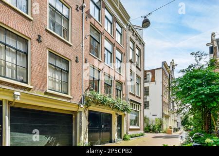 una strada cittadina con auto parcheggiate sul lato e un edificio di appartamenti sul retro accanto alla strada Foto Stock