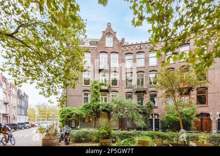 Amsterdam, Paesi Bassi - 10 aprile, 2021: Un appartamento nei paesi bassi con un sacco di piante e alberi su entrambi i lati, c'è una bicicletta parcheggiata accanto ad esso Foto Stock