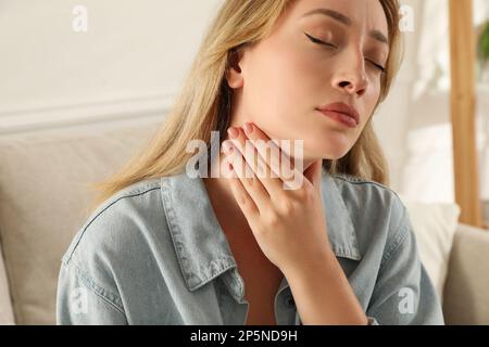 Giovane donna che fa l'esame di auto della tiroide nel paese Foto Stock