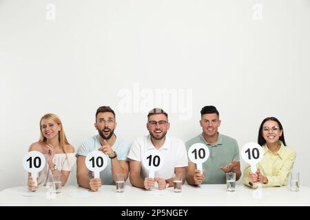 Gruppo di giudici con i segni con il punteggio più alto a tavola su sfondo bianco Foto Stock
