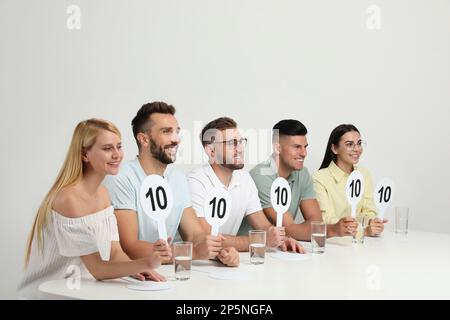 Gruppo di giudici con i segni con il punteggio più alto a tavola su sfondo bianco Foto Stock