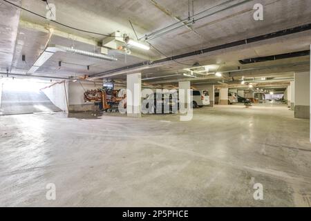 un parcheggio vuoto con auto parcheggiate nel garage e due uomini che lavorano sui loro computer portatili allo stesso tempo Foto Stock