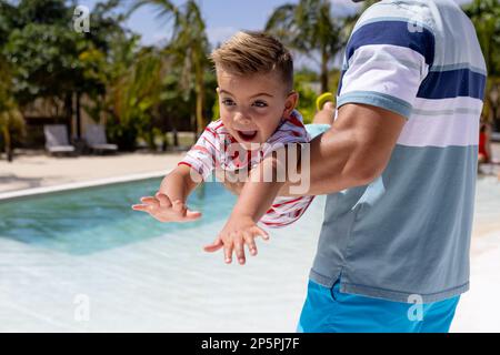 Buon padre e figlio biraciale che giocano in piscina Foto Stock