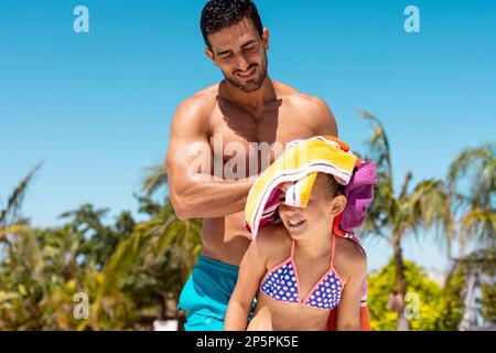 Felice padre e figlia biraciale utilizzando asciugamano presso la piscina Foto Stock