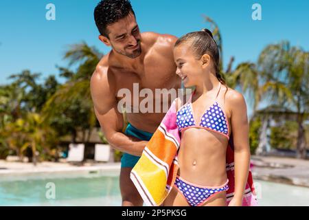 Felice padre e figlia biraciale utilizzando asciugamano presso la piscina Foto Stock