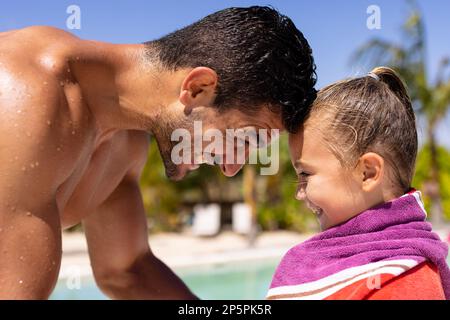 Felice padre e figlia biraciale utilizzando asciugamano presso la piscina Foto Stock