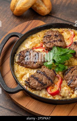 Polpette con salsa all'alinazik. Polpette turche tradizionali su purea di melanzane in padella di ghisa Foto Stock