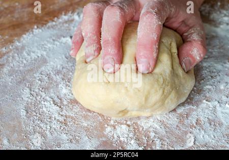 Impastare a mano la pasta cruda Foto Stock