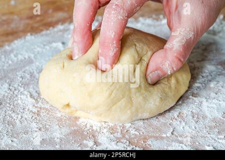 Impastare a mano la pasta cruda Foto Stock