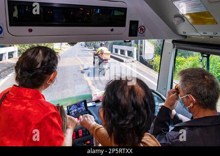 Autista e passeggeri che guardano attraverso il parabrezza su un autobus navetta elettrico, Bangkok, Thailandia Foto Stock