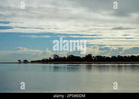 Vista di prima mattina attraverso le calme acque di Moreton Bay fino all'isola di Coochiemudlo. Cielo blu con nuvole. Foto Stock