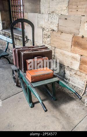 Vecchie auto e valigie a Pickering Station, una stazione a tema degli anni '30 da non perdere che ti riporterà indietro nel tempo all'era del vapore. Foto Stock