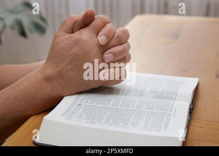 mani piegate su una bibbia Foto Stock