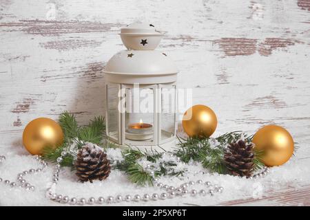 Decorazione natalizia, lanterna con baubles, rami di abete, coni di pino, neve artificiale e cappelletto Foto Stock