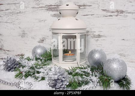 Decorazione natalizia, lanterna con baubles, rami di abete, coni di pino, neve artificiale e cappelletto Foto Stock