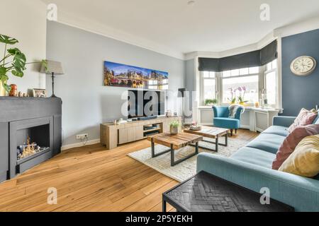 Comodo divano blu posto su tappeto contro la parete con TV e camino in  appartamento luminoso ed elegante con una porta aperta che conduce alla  cucina luminosa Foto stock - Alamy