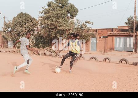 Ouagadougou, Burkina Faso. Alcuni uomini stanno giocando una partita di calcio in un sobborgo della capitale Foto Stock