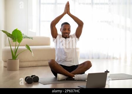 Uomo nero meditando a casa, guardando video su Internet Foto Stock