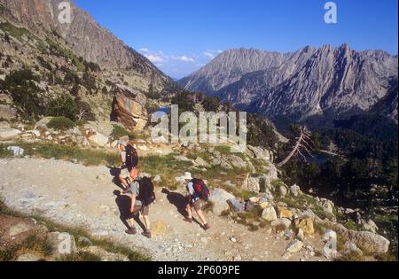 Gli escursionisti salgono al rifugio Amitges, sullo sfondo a destra Encantats montagne, Aigüestortes i Estany de Sant Maurici Parco Nazionale, Pirenei, Lleida p Foto Stock
