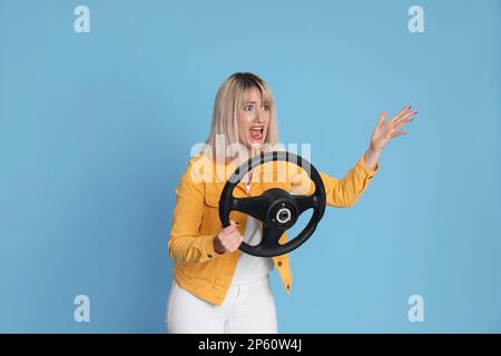 Donna emozionale con volante su sfondo azzurro Foto Stock