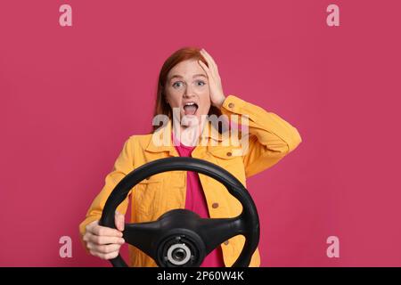 Giovane donna emozionale con volante su sfondo cremisi Foto Stock