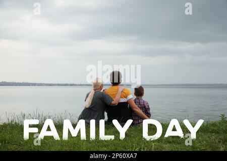 Il bambino ed i nonni che passano il tempo insieme vicino al fiume, vista posteriore. Buon giorno della famiglia Foto Stock