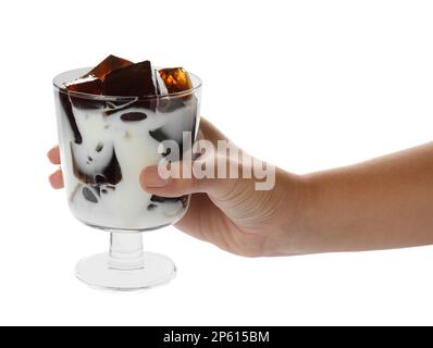 Donna che tiene un bicchiere di latte con deliziosa gelatina d'erba su sfondo bianco, primo piano Foto Stock