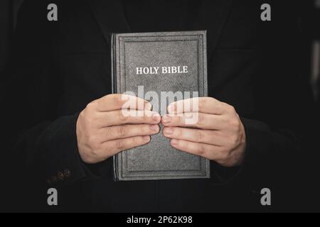 La Sacra Bibbia nelle mani degli uomini. Il concetto di fede e religione. la fede cristiana. il sacerdote sta tenendo un libro. Foto Stock