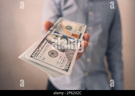 Uomo d'affari con dollari americani. Un uomo tiene in mano i dollari americani. Il capo paga lo stipendio. Il concetto di corruzione e corruzione, dando m Foto Stock