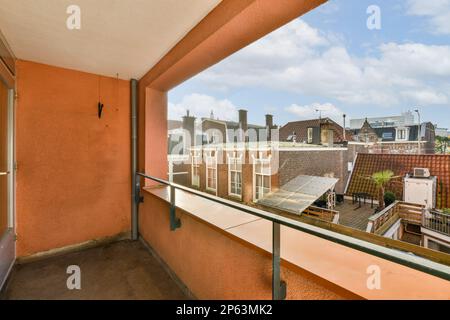 un balcone con pareti arancioni e rifiniture bianche sulle ringhiere, come si vede dall'interno di un appartamento a melbourne Foto Stock