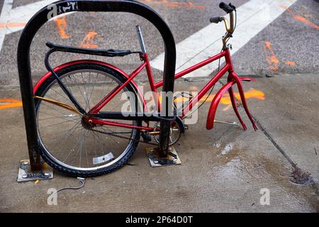 Prevenzione o vittima di furto di parti di bicicletta in questa scena di una bicicletta parziale incatenata al portabiciclette. Foto Stock