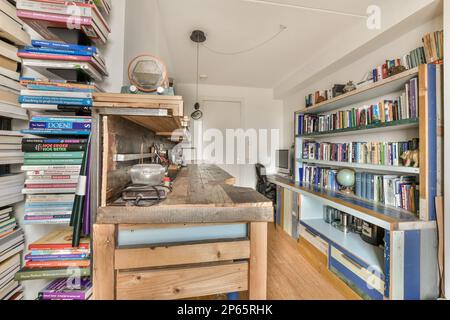 una camera con molti libri sugli scaffali e una libreria aperta nell'angolo vicino all'isola della cucina Foto Stock